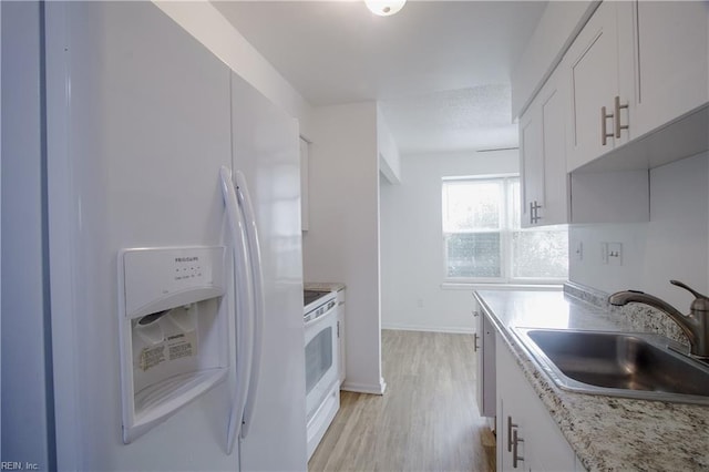 kitchen with sink, white appliances, light hardwood / wood-style flooring, white cabinetry, and light stone countertops