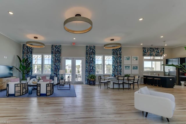 living room with crown molding, light wood-type flooring, and french doors