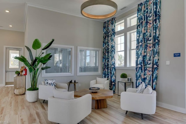 living room featuring ornamental molding, a healthy amount of sunlight, and light wood-type flooring