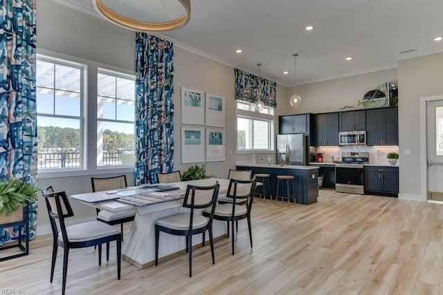 dining room with crown molding, light hardwood / wood-style flooring, and a high ceiling