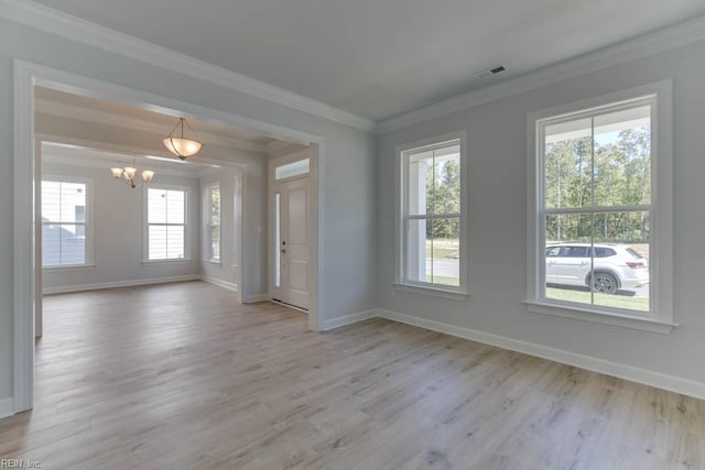 empty room featuring crown molding, a chandelier, and light wood-type flooring