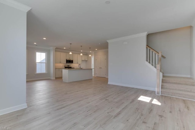 unfurnished living room with ornamental molding, sink, and light wood-type flooring