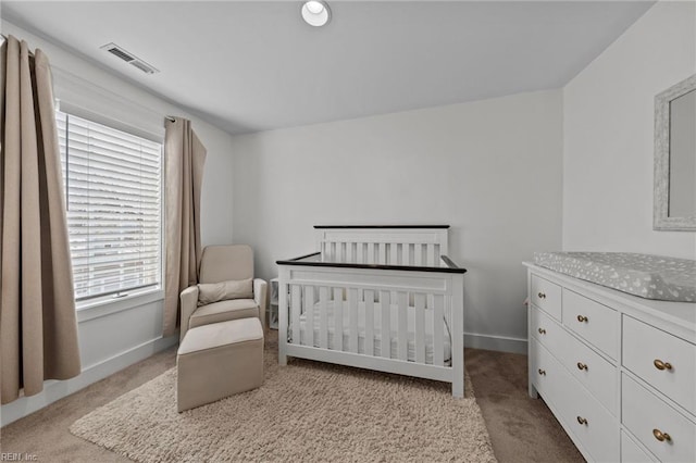 bedroom with light carpet and a nursery area