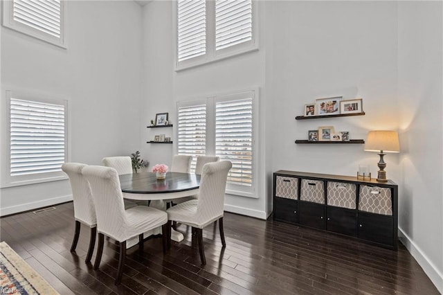 dining room with dark hardwood / wood-style floors and a towering ceiling