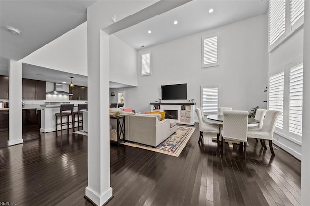 living room with decorative columns, dark wood-type flooring, and a towering ceiling