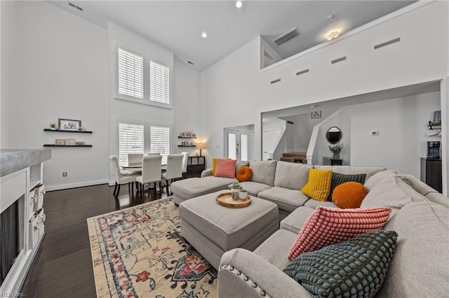 living room with a towering ceiling and dark hardwood / wood-style flooring