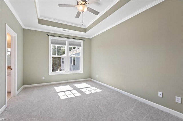 carpeted empty room featuring a raised ceiling, ornamental molding, and ceiling fan