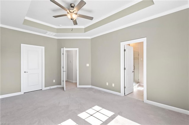 unfurnished bedroom featuring light carpet, connected bathroom, ornamental molding, and a raised ceiling