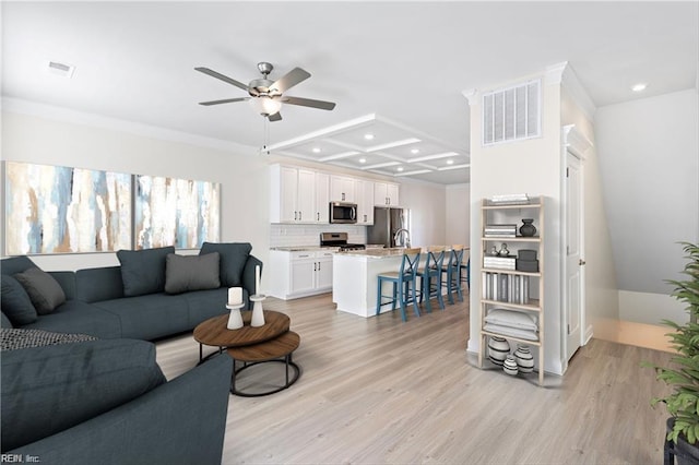 living room featuring crown molding, coffered ceiling, ceiling fan, and light hardwood / wood-style flooring