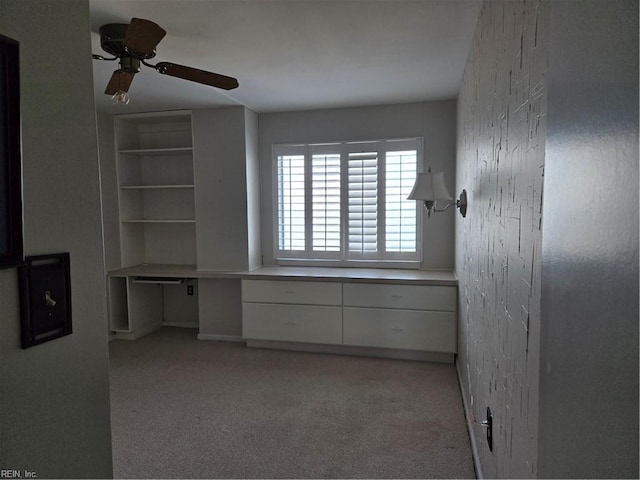 interior space featuring ceiling fan, built in desk, and light carpet