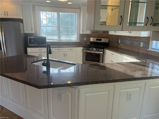 kitchen featuring sink, stainless steel appliances, dark stone counters, and white cabinets