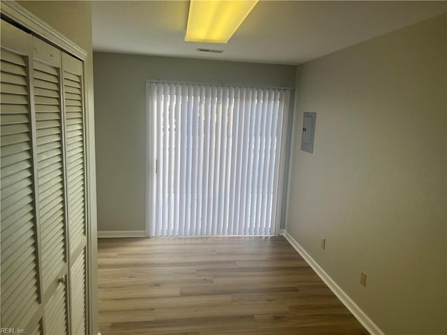 unfurnished bedroom with electric panel, light wood-type flooring, and a closet