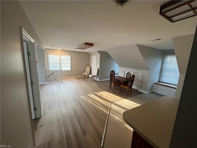 additional living space featuring vaulted ceiling and light hardwood / wood-style floors