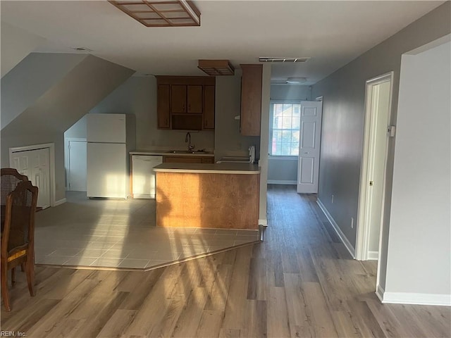 kitchen with sink, light hardwood / wood-style flooring, stainless steel dishwasher, and white fridge