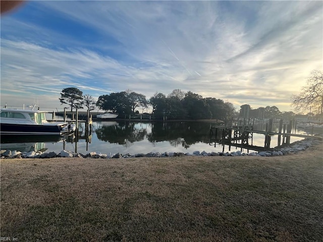 view of dock with a water view and a lawn