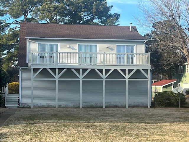 rear view of property featuring a balcony and a yard