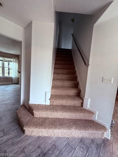 stairway featuring a textured ceiling