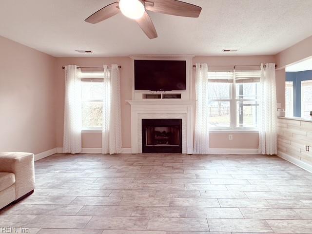 unfurnished living room featuring ceiling fan, plenty of natural light, and a textured ceiling