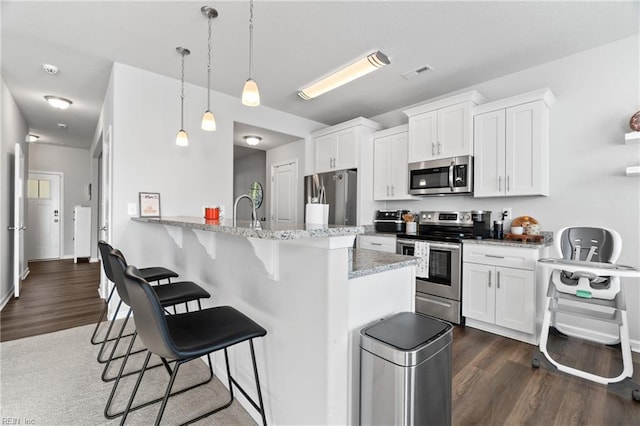 kitchen with white cabinetry, decorative light fixtures, stainless steel appliances, and kitchen peninsula