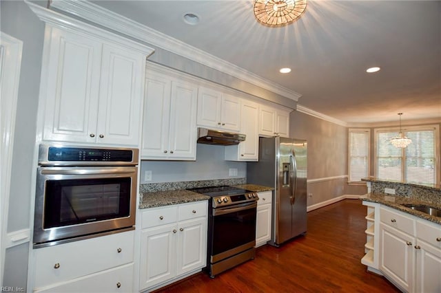 kitchen with pendant lighting, white cabinets, dark stone counters, stainless steel appliances, and crown molding