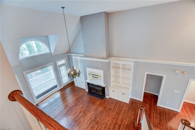 living room featuring dark hardwood / wood-style flooring, a notable chandelier, a fireplace, and high vaulted ceiling