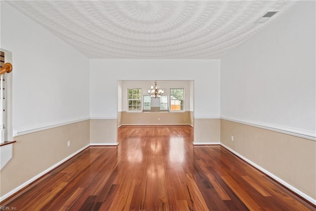 spare room featuring a chandelier, a textured ceiling, wood finished floors, and baseboards