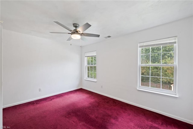 carpeted spare room featuring baseboards, visible vents, and ceiling fan