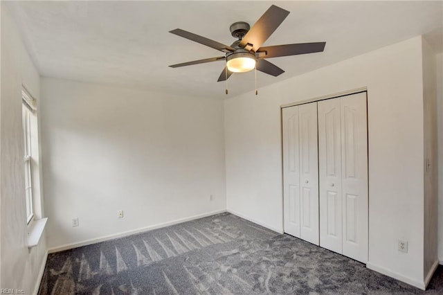 unfurnished bedroom with baseboards, dark carpet, ceiling fan, and a closet