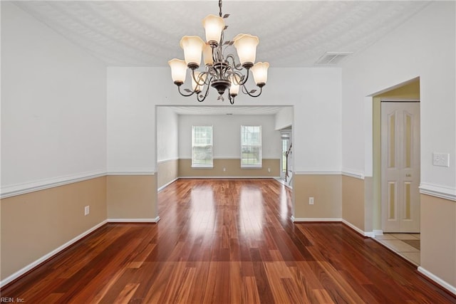 unfurnished dining area with baseboards, dark wood-type flooring, visible vents, and an inviting chandelier