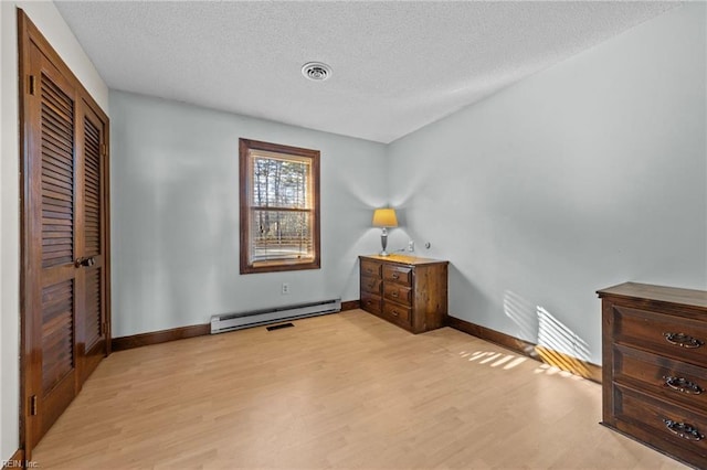 bedroom featuring a baseboard radiator, light hardwood / wood-style flooring, and a textured ceiling