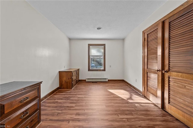 unfurnished bedroom with a baseboard radiator, a closet, and wood-type flooring