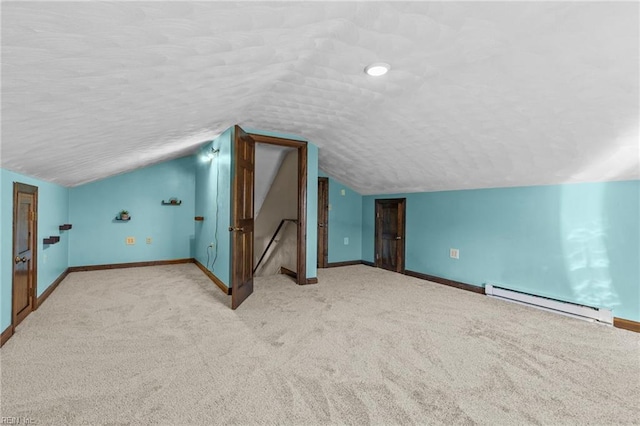 additional living space featuring a baseboard radiator, vaulted ceiling, light colored carpet, and a textured ceiling