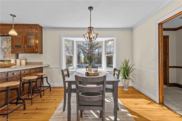 dining area with ornamental molding, a wealth of natural light, a notable chandelier, and light wood-type flooring