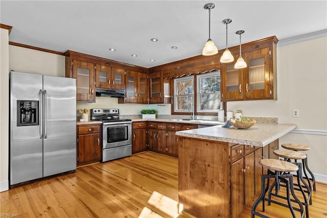 kitchen featuring pendant lighting, sink, light hardwood / wood-style floors, kitchen peninsula, and stainless steel appliances