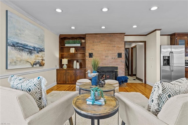 living room with ornamental molding, a brick fireplace, and light wood-type flooring