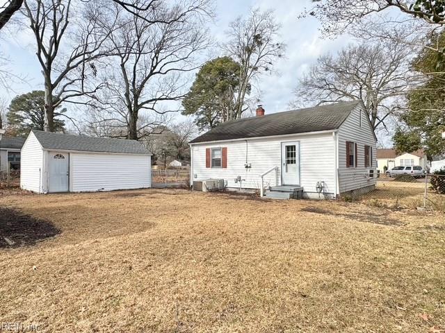 back of property with a lawn and an outdoor structure