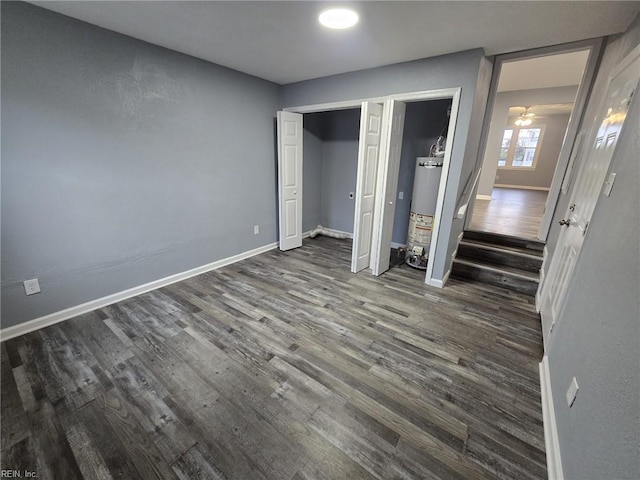 unfurnished bedroom with dark wood-type flooring, water heater, and multiple closets