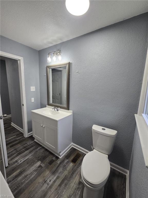 bathroom featuring wood-type flooring, vanity, a textured ceiling, and toilet