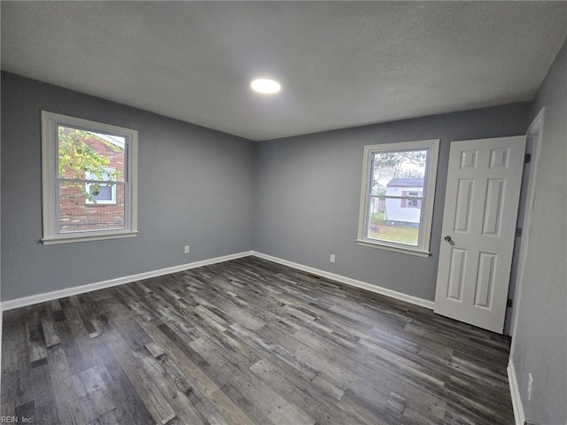 unfurnished room featuring a healthy amount of sunlight, dark hardwood / wood-style flooring, and a textured ceiling