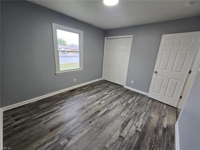 unfurnished bedroom with dark wood-type flooring and a closet