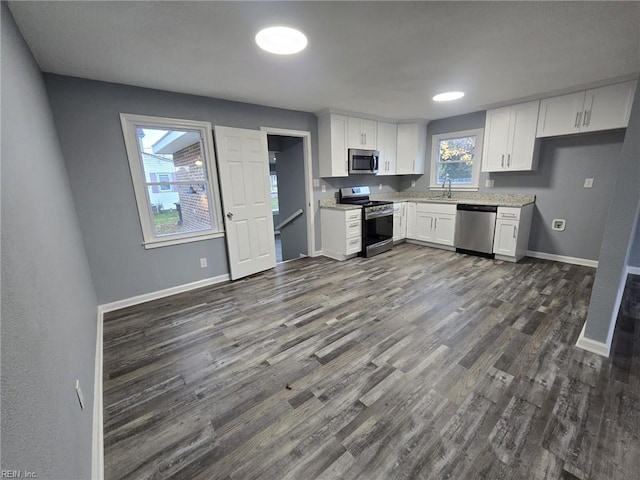 kitchen with dark hardwood / wood-style flooring, sink, stainless steel appliances, and white cabinets