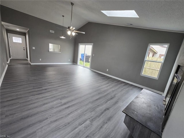 unfurnished living room featuring vaulted ceiling with skylight, hardwood / wood-style floors, ceiling fan, and a textured ceiling