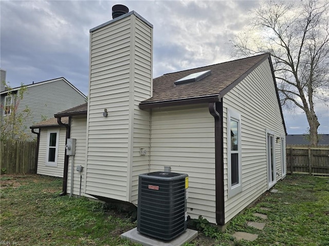 back of property featuring a lawn and central air condition unit