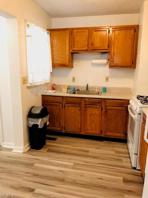 kitchen with sink, white range with gas stovetop, and light wood-type flooring