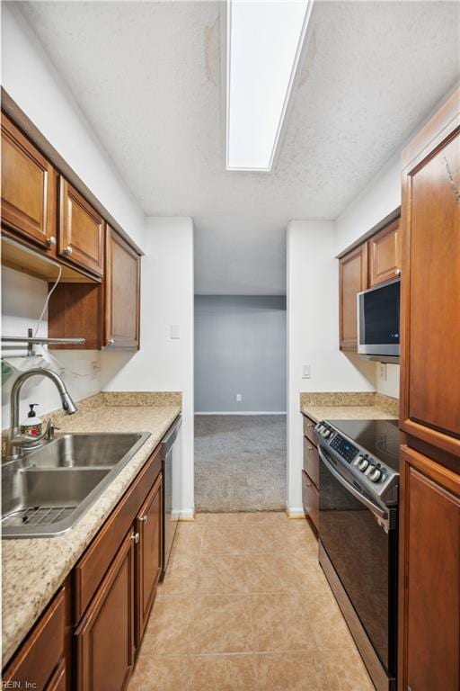 kitchen featuring light colored carpet, appliances with stainless steel finishes, sink, and a textured ceiling