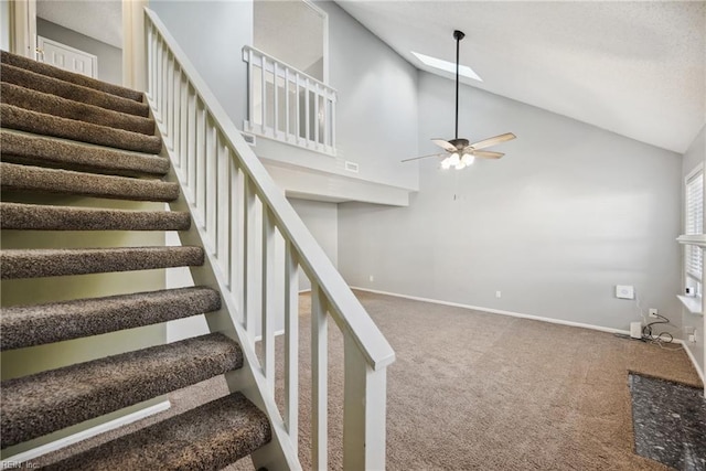 stairs featuring a skylight, high vaulted ceiling, ceiling fan, and carpet