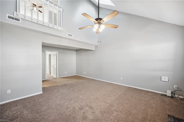 carpeted empty room with a towering ceiling and ceiling fan