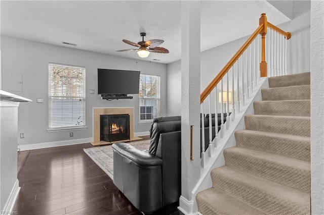 living room featuring ceiling fan, a textured ceiling, and dark hardwood / wood-style flooring