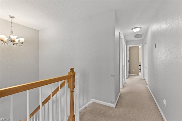 corridor featuring light carpet and an inviting chandelier