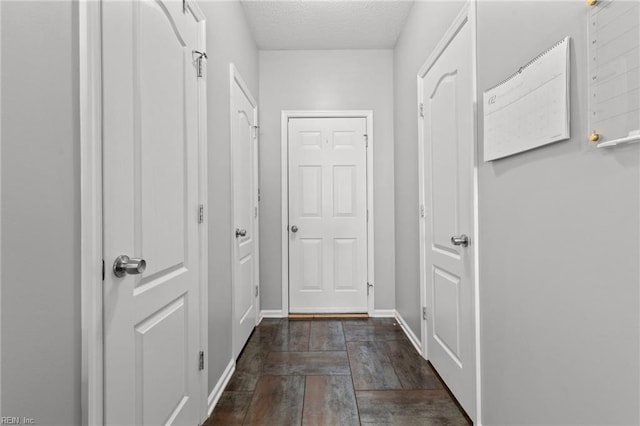 corridor with dark hardwood / wood-style flooring and a textured ceiling